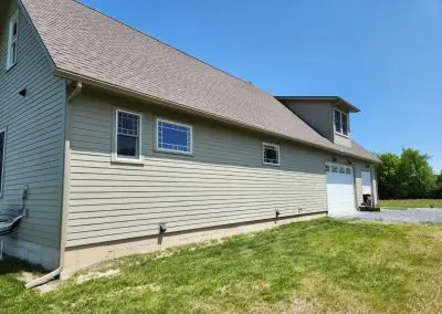Sage green barn-style garage in Addison County VT with white seamless gutters