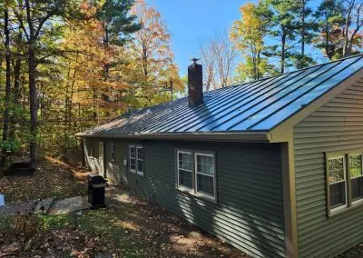 Green ranch home near Crown Point NY with a standing seam metal roof and seamless gutters